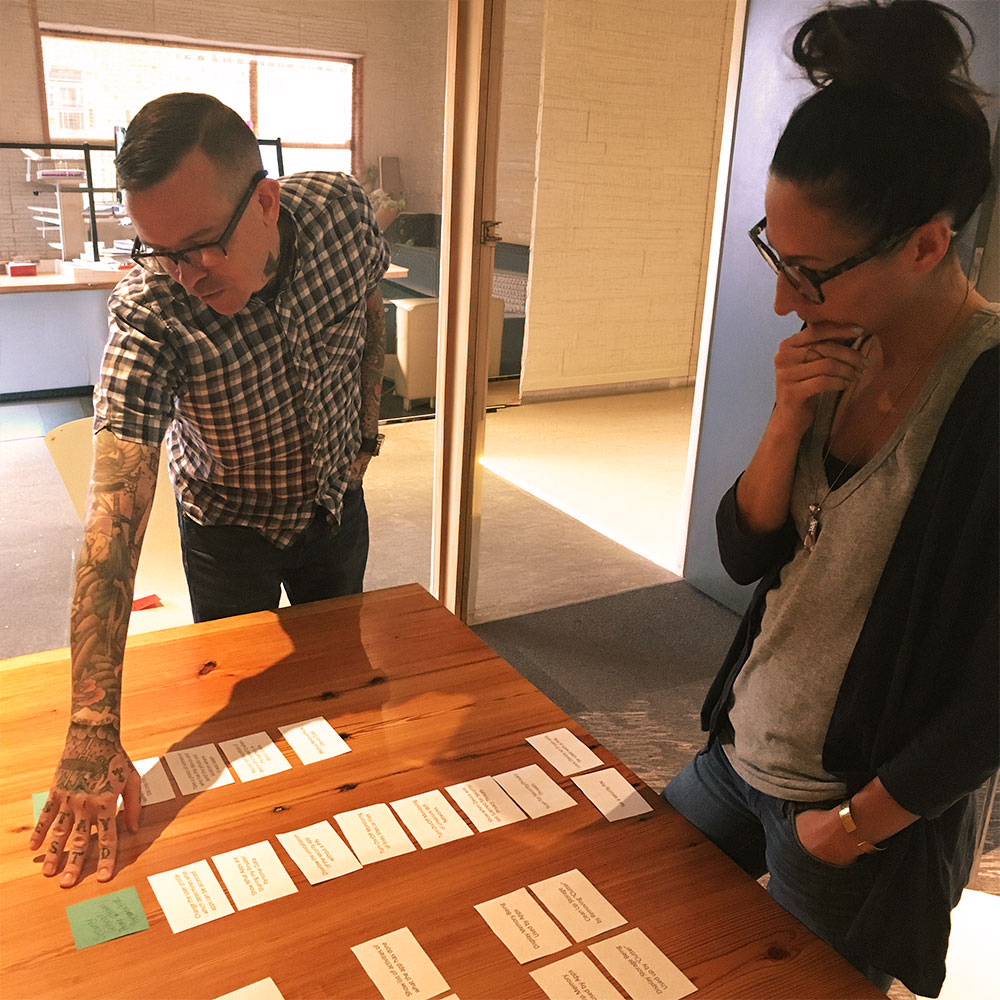 Card sorting session: two people arranging and grouping cards on a table during UX research